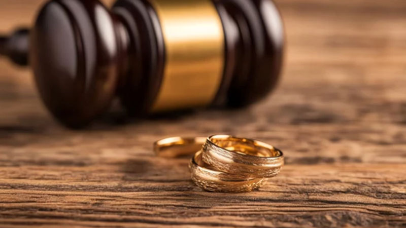 a gavel with wedding rings below